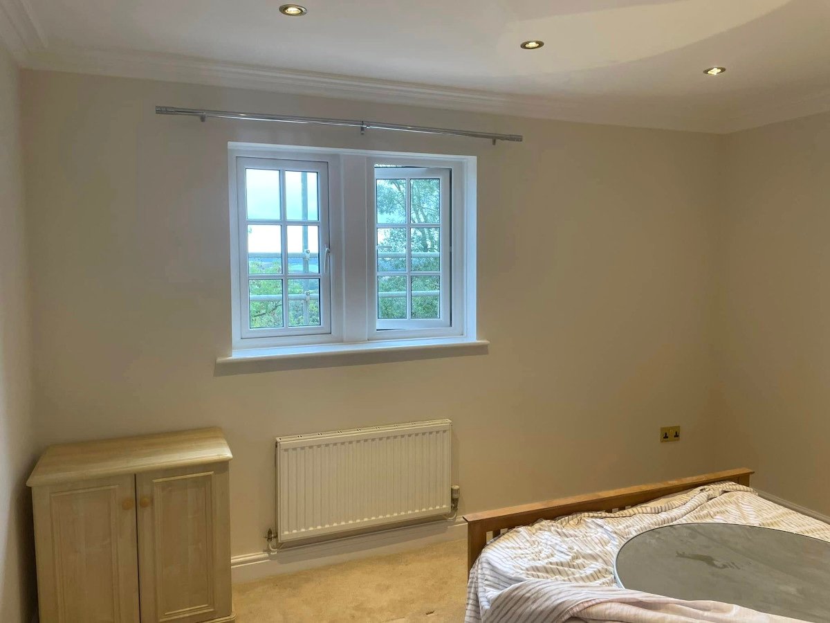 Bedroom with cream painted walls and double windows in Bassaleg executive home by Orchid Decor