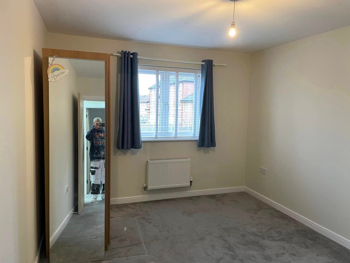 Painter working on cream painted walls in bedroom, decorating costs in Caerleon by Orchid Decor