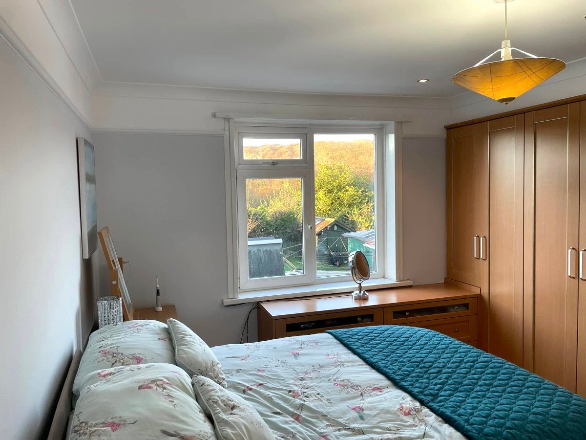 Bedroom conversion with grey painted walls and garden window view in Newport