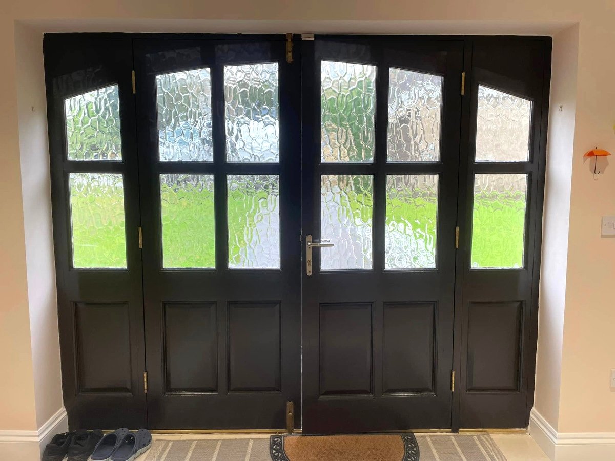Hallway with cream painted walls and black French doors in Newport