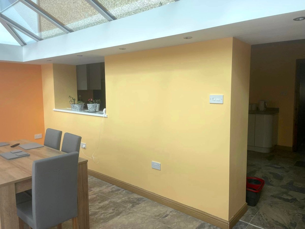 Kitchen cabinet painting in Newport by Orchid Decor, bright yellow painted kitchen with skylight and pillar