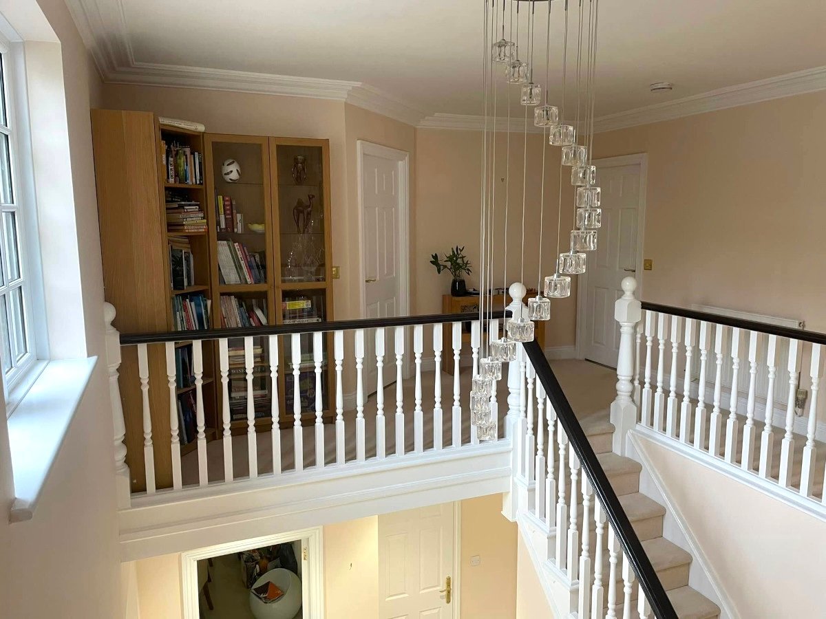 Painted landing with beige walls, chandelier and bookshelf — interior painting by Orchid Decor Usk